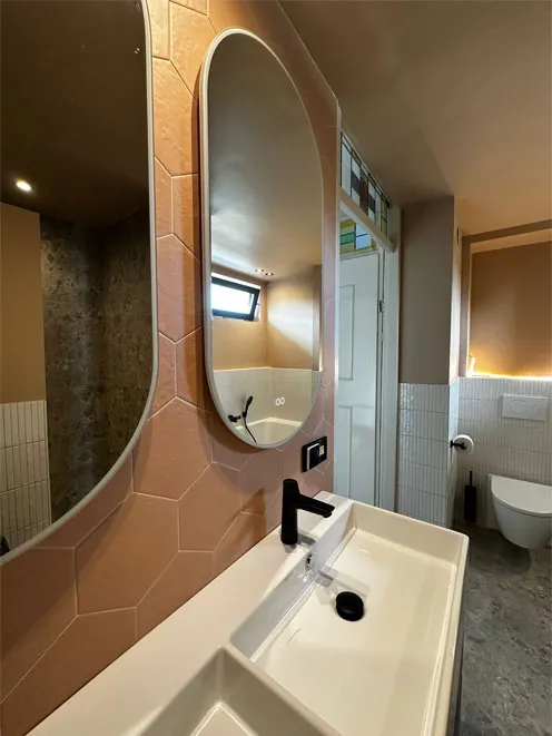 Badkamer met ovale spiegel en roze tinten