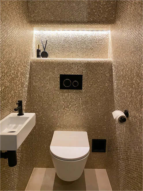 Toiletruimte met verlichte nis en gouden accenten